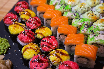 Set of rolls on a black plate with wasabi and ginger