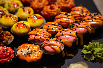 Hot baked set of rolls on a black plate with wasabi and ginger