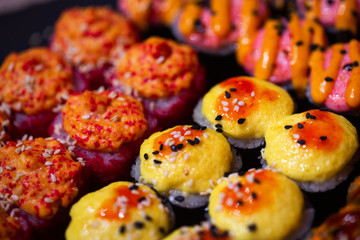 Hot baked set of rolls on a black plate with wasabi and ginger
