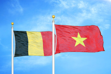 Belgium and Vietnam two flags on flagpoles and blue cloudy sky