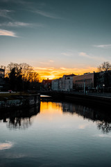 Fototapeta premium River in the downtown district at colorful moody evening sunset light and water reflection. Calm and empty evening scene. Downtown of a city, Braunschweig , Germany