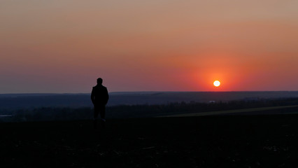 A man watches the sunset. Sunset on the horizon. The sky is pink.