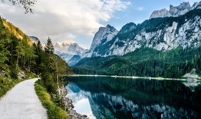 Fototapeta na wymiar View on lake Gosau, alps mountains with green fields and cloudy sky. Gosau, Salzburger land nearby Salzburg, Austria