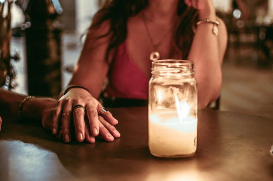 coppia che si tiene per mano al tavolino di un ristorante al lume di candela, amore, romantico