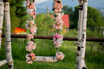 Wedding swing decorated with flowers hanging on the branches