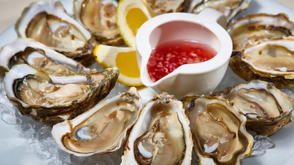 Opened fresh oysters with lemon on dish. Shallow dof