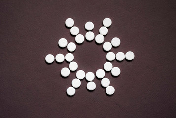 Fototapeta na wymiar White round pills on a brown background.