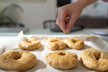 Hand sprinkling salt onto homemade bagels