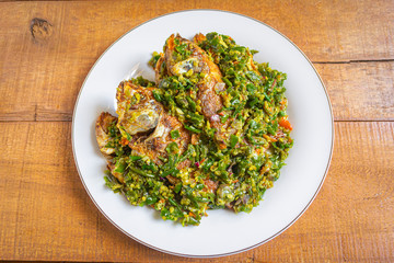 Ikan nila cabe hijau is indonesian food. made from fish, green chilies, garlic and other ingredients. has a savory and spicy taste. on white plate