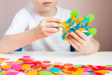 Obraz na płótnie Canvas A child plays with a round colored mosaic. Game process close up. Hands close up. Quarantined home art. The development of fine motor skills.