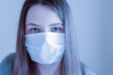 Sad young woman with protection medical mask looking at camera. Stay at home for quarantine to prevent coronavirus spread. Concept for protect from infection, respiratory disease, virus or bacteria