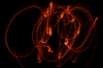 Vibrant neon gold color in abstract swirls on a black background. Light painting