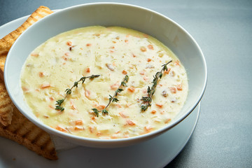 Tasty cheese cream soup with mushrooms and bacon, croutons in a white bowl isolated on a black background. Top view