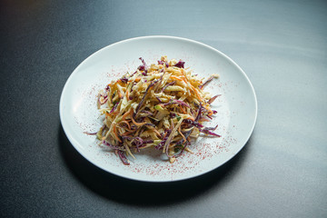 Vegetarian Cole Slow Salad with creamy dressing, cabbage, carrots and spices on a white plate isolated on black background. Close up
