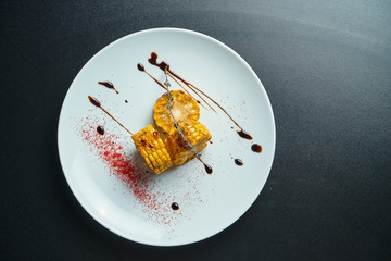 Grilled corn with spices on a white plate. Top view. Selective focus