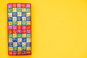 Multicolored little gift boxes on yellow background. Top view. Copy, empty space for text