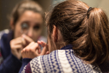 Woman putting on makeup in the mirror during confinement quarantine