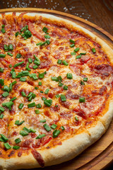 Baked pizza with salami chorizo with red sauce and melted cheese on a wooden background in a composition with ingredients. Close up