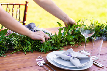 Preparing for an open-air party. Girl decorates tables with fresh flowers. Decoration Details