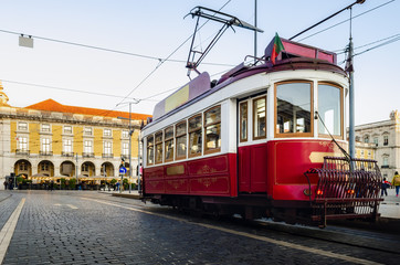 Naklejka na ściany i meble Traditional old red tramcar cable electric trolley stops in Praca do Comercio, main square of the Baixa district of Lisbon, Portugal