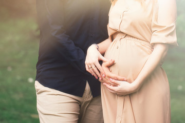 Cropped image of beautiful pregnant woman and her handsome husband hugging the tummy