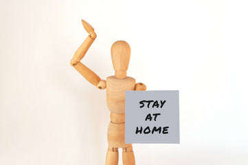 World coronavirus pandemic,2019-ncov. wooden man is isolated on a white background holds a sign with the inscription: stay home. Outbreak Defense Concept. Copy Space.