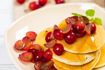 Healthy Homemade Classic American Pancakes with Sliced Red Grapes and Maple Syrup Close Up. Selective focus.