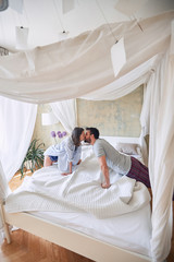 Loving couple kissing in the morning while making the bed. © luckybusiness