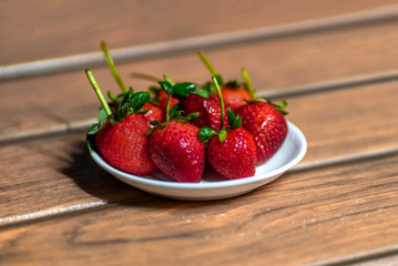 Fresas frescas organica sobre un bol en una tabla de madera con ligero desenfoque en el fondo