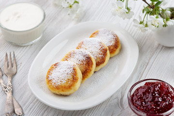 Syrniki - fritters cheesecakes from cottage cheese  with jam and sour cream. Ukrainian and Russian cuisine.