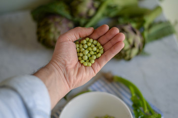 Naklejka na ściany i meble Male hand showing freshly harvested green peas: concept of healthy food and natural lifestyle