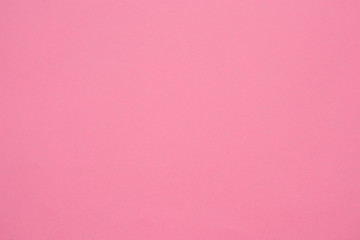 A sheet of paper is a soft pink, coral color. Close-up. The background is a muted, dusty shade. Daylight. Fine paper texture. Space for text