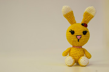 Amigurumi yellow hare sitting on a white background. Needlework concept.