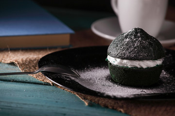 sweet green muffin with whipped cream photographed next to a cup of coffee on a turquoise wooden 