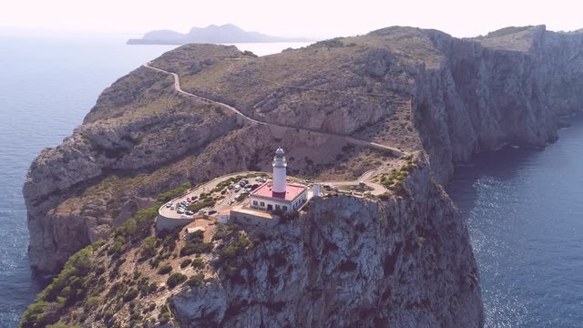 Lighthouse on rocky seashore with curved road
