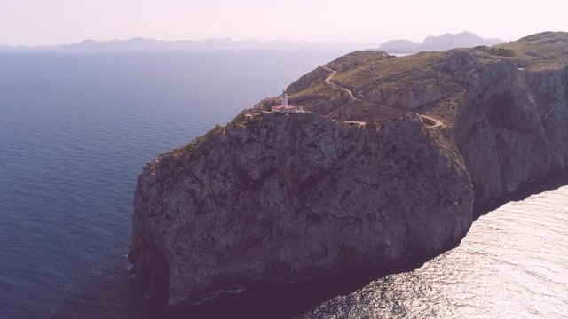 Lighthouse on rocky seashore with curved road