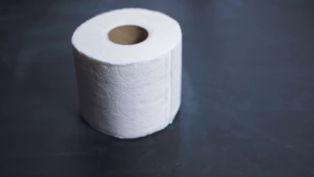 A roll of toilet paper slowly falls onto the table. Toilet paper shortages during a crisis and pandemic. The financial crisis 2020.