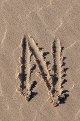 the letter n written in beach sand