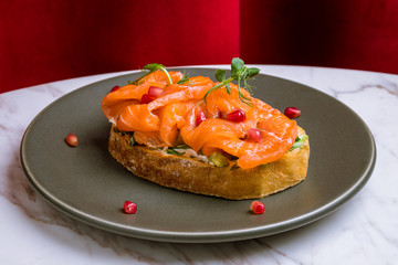 Bruschetta with salmon and cheese on black plate