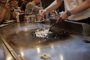 He stir fry food in a flat pan. cook tools and flat pad teppanyaki japanese food