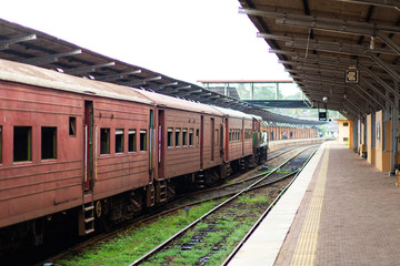 Empty platform of a railway station in Sri Lanka. Old rusty train cars. It looks like an abandoned...