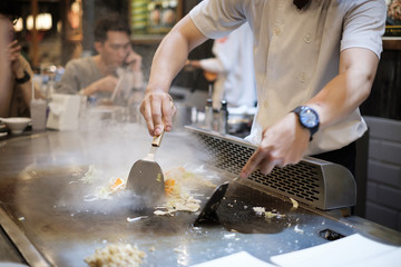 He stir fry food in a flat pan. cook tools and flat pad teppanyaki japanese food