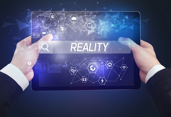 Close-up of a tablet searching REALITY inscription, hi-tech computing concept