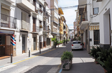 Obraz premium The white car and green decorative plants on the empty street of the small town in Europe on the sunny day