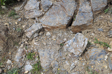 The different blue-grey natural stones and small green grass on the ground on the mountain path