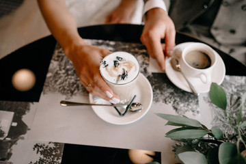Couple in love holding hands with coffee on white wooden table. Photograph taken from above, top view with copy space