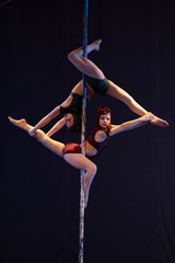 Fototapeta na wymiar The duo of a girl athlete gymnasts show a pair acrobatic performance on the pylon.
