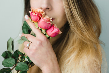 Portrait of a beautiful young woman in her wedding day smelling a beautiful bouquet of pink roses...