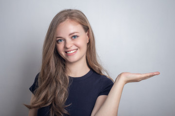 Smiling young caucasian girl woman showing pointing at white copy space 