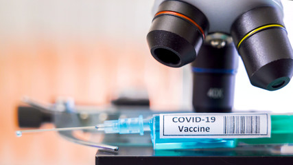Fototapeta na wymiar Closer look of the microscope with the Covid-19 vaccine for coronavirus 